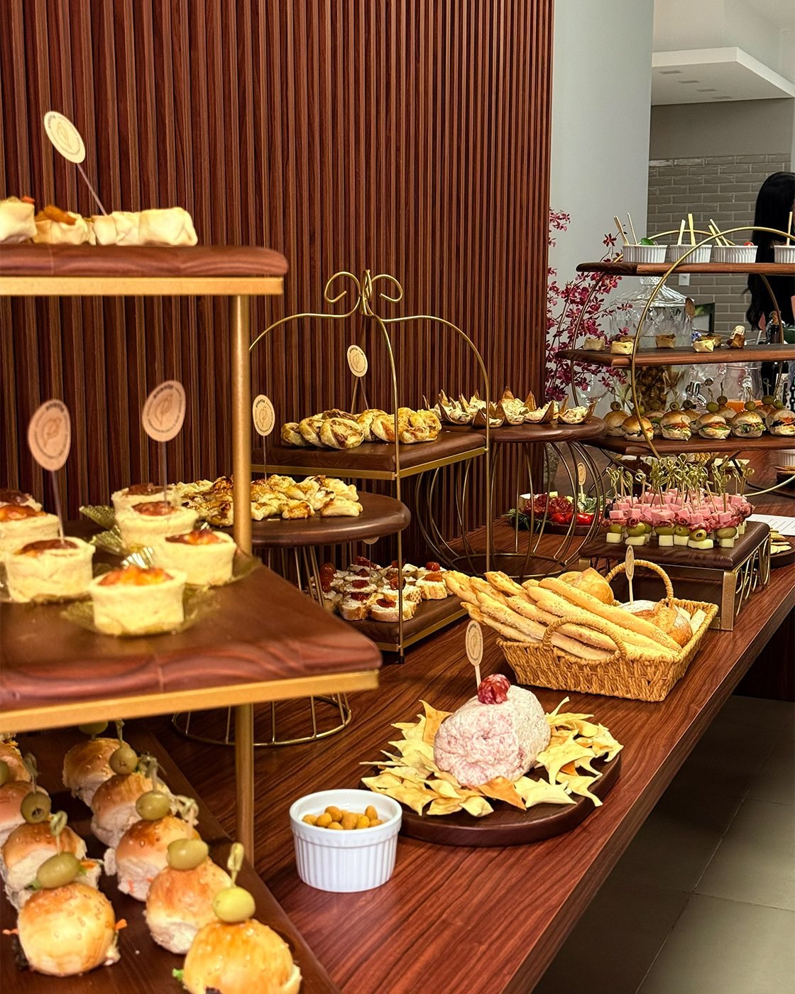 Mesa de coffee break com quiches, salgados e mini sanduíches
