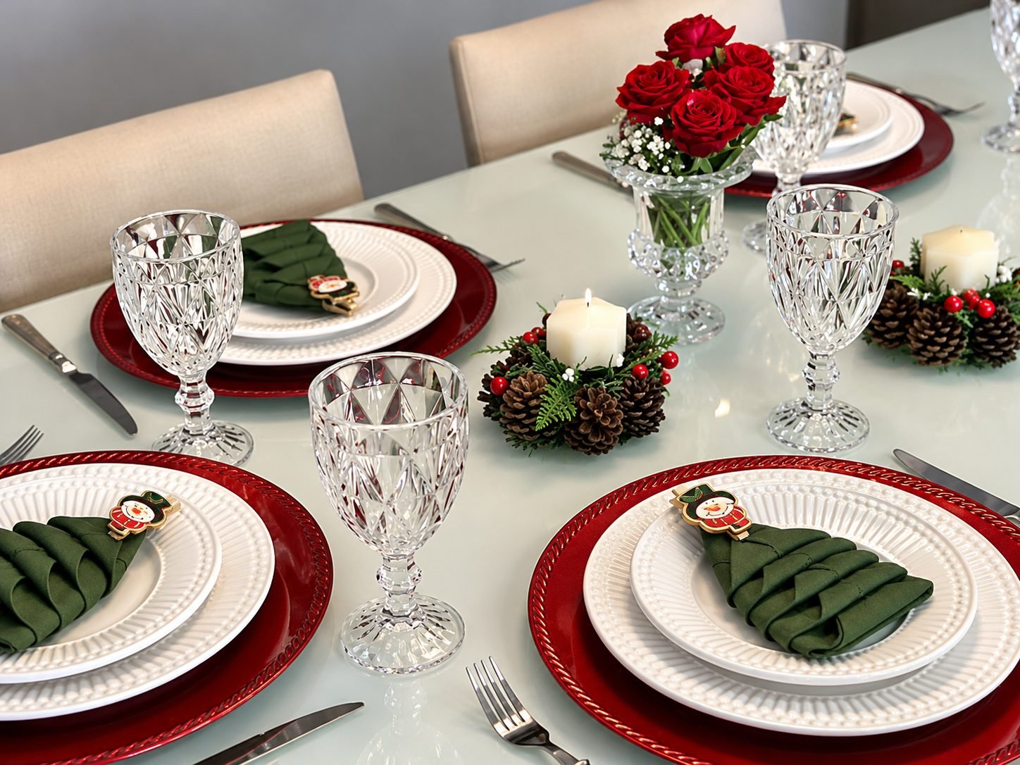 Mesa posta festiva com cristais, rosas e sousplats vermelhos